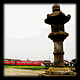 大きな灯籠の後ろに真っ赤な電車が走る